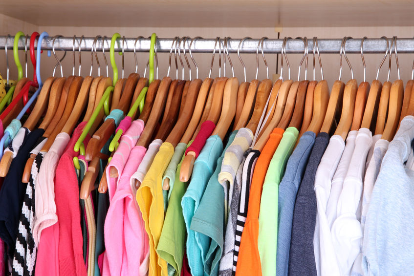 Various coloured clothes in a wardrobe